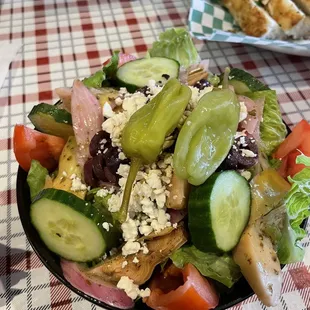 Small Greek salad with a side of focaccia bread.