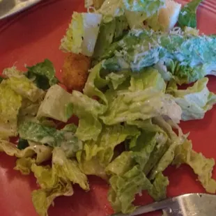 Half of a small caeser salad and tasty pizza.