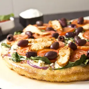 a pizza with olives, tomatoes, and cheese