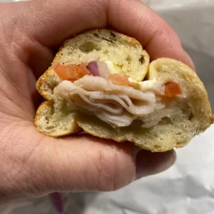 a hand holding a half eaten sandwich