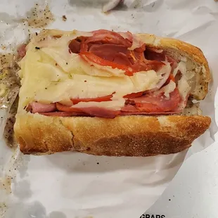 a half eaten sandwich on a piece of wax paper