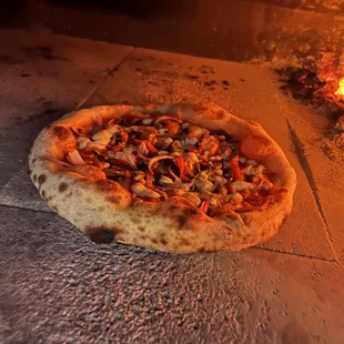 a pizza cooking in a brick oven