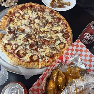 a pizza with pepperoni, cheese, and chicken wings