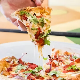 a person taking a slice of pizza