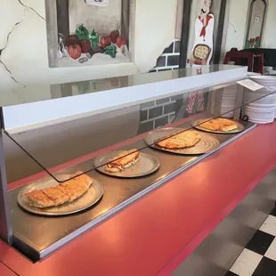 a row of pizzas on the counter
