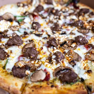 Via Tuscana (pesto sauce, whole-milk mozzarella cheese, mushrooms, spinach, sun-dried tomatoes, feta cheese and garlic) w/ added Sausage
