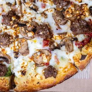 Via Tuscana (pesto sauce, whole-milk mozzarella cheese, mushrooms, spinach, sun-dried tomatoes, feta cheese and garlic) w/ added Sausage