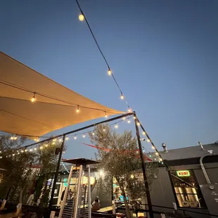 the outside of a restaurant with string lights