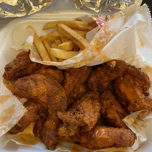 chicken wings and french fries in a styrofoam container