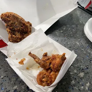 two pieces of fried chicken in a paper container