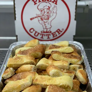 a tray of bread rolls in front of a pizza cutter