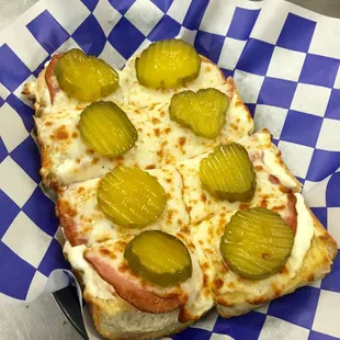 a slice of pizza with pickles on it