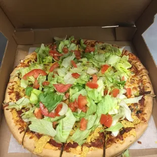 a pizza with lettuce and tomatoes
