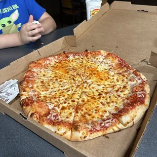 a young boy sitting at a table in front of a large pizza