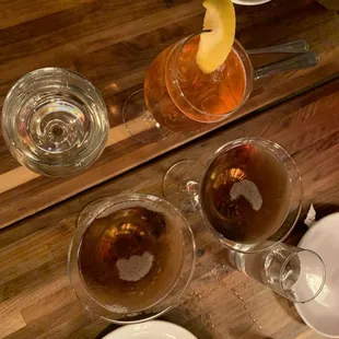 a wooden table with glasses of wine, plates and utensils