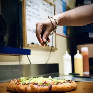 a hand reaching for a piece of pizza