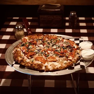 a large pizza on a checkered tablecloth
