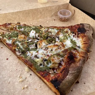 Pizza by the slice where I added pesto, mushrooms and grilled chicken.
