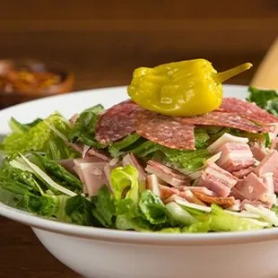 a bowl of salad with a pickle on top