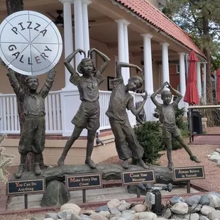a statue of a group of people holding a clock