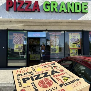a person holding up a pizza box