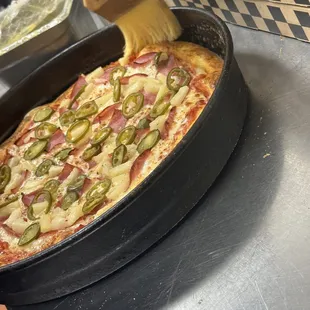 a person putting toppings on a pizza