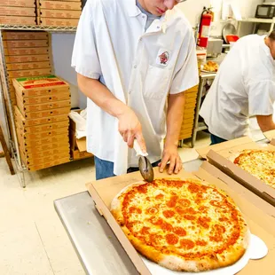 a man cutting a pizza in a kitchen