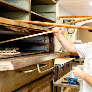 a man putting a pizza in an oven