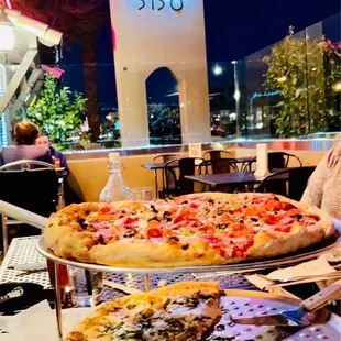 a woman sitting at a table with several pizzas