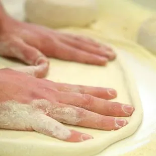 a person kneading dough on a table