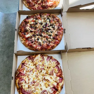 three different pizzas in boxes