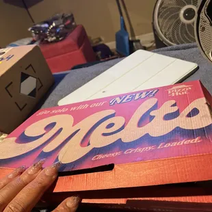 a hand holding a pizza box