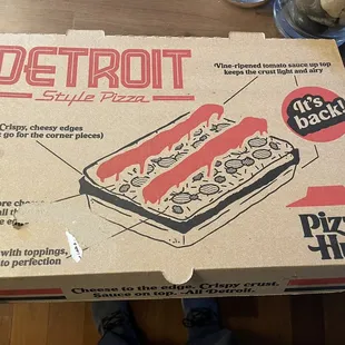 a person holding a box of pizza