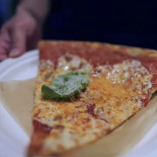 a slice of pizza on a paper plate