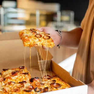 a person holding a slice of pizza