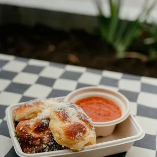 a plate of pizza rolls and a bowl of tomato sauce