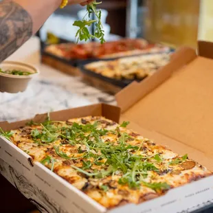 a person taking a slice out of a pizza box