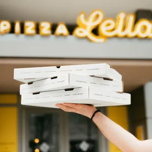 a woman holding a stack of pizzas