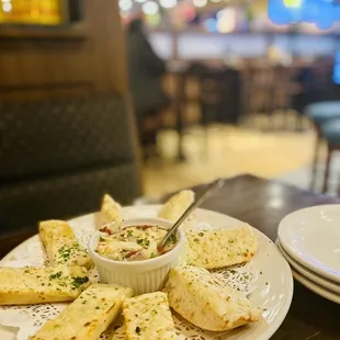 a plate of breadsticks and a bowl of dip