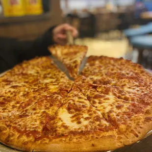 a person cutting a slice of pizza