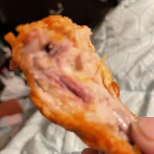 a hand holding a piece of pizza