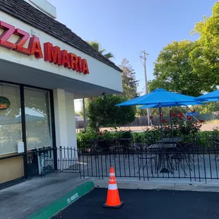 the outside of a restaurant with tables and umbrellas