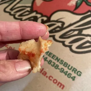 a hand holding a half eaten pizza