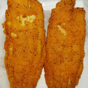 two pieces of fried fish on a white plate