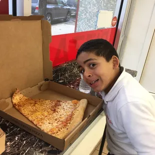 a boy sitting in front of a pizza box