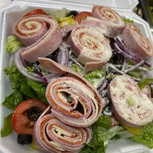 a salad with ham, lettuce, tomatoes, and cheese