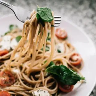 a plate of spaghetti with tomatoes and spinach