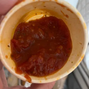 a hand holding a bowl of sauce