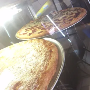 two pizzas in a display case