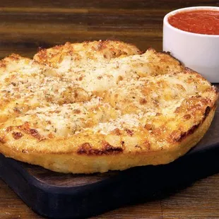 a pizza and a bowl of tomato sauce